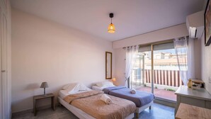 Habitación de hotel con dos camas, una mesita, una lámpara, un espejo y un balcón con vistas.