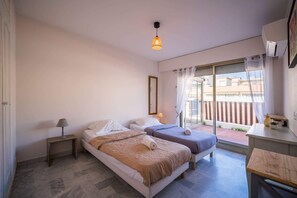 A hotel room with two beds, a small table, a lamp, a mirror, and a balcony with a view. - Bel Azur (Antibes)