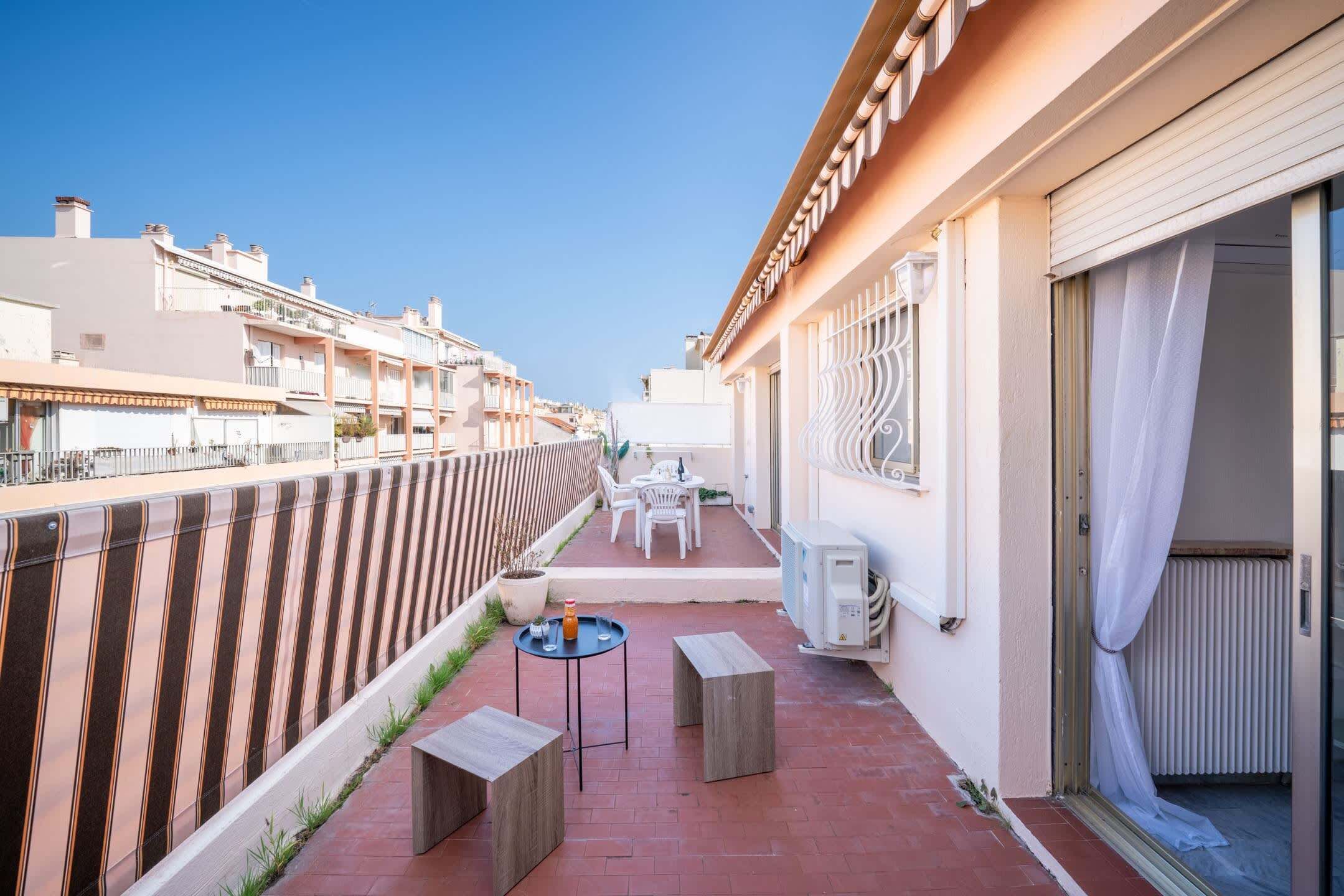 Ein Korridor, der zu einem Balkon mit Tisch und Stühlen, einem Heizkörper und einem Fenster mit schmiedeeisernen Gitterstäben führt.