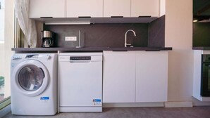 Cocina compacta equipada con lavadora, lavavajillas y fregadero.