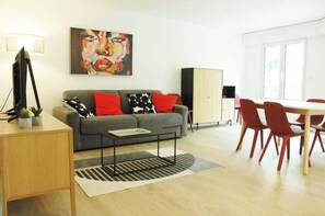 Ein modernes Wohnzimmer mit Sofa, Couchtisch und Essbereich.