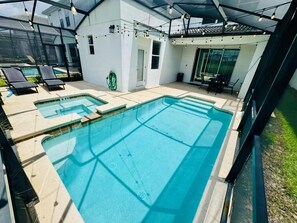 Ein Schwimmbeckenbereich mit zwei Pools, einem überdachten Sitzbereich und einer verglasten Terrasse.