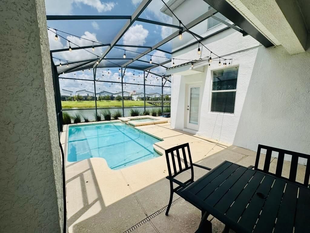 A covered outdoor area with a pool, a table, and chairs.