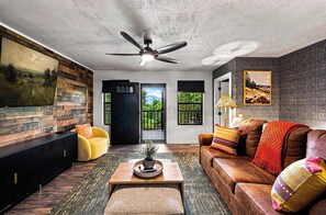 A living room with a ceiling fan, a sofa, a coffee table, and a painting on the wall. - Rolling Hills Retreat | Hot Tub • Fire Pit • Sauna (Pigeon Forge)
