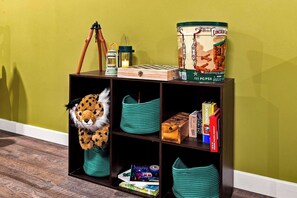 Una estantería con diversos objetos, incluyendo un peluche de leopardo, una lata de Lincoln Lager y varios libros.