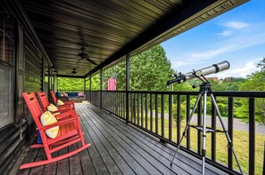 Eine Holzterrasse mit Schaukelstühlen und einem auf Stativ montierten Teleskop.