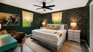 Un dormitorio con cama, mesitas de noche, escritorio y una silla.