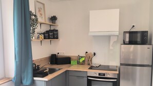 Een moderne keuken met een roestvrijstalen koelkast, een magnetron, een broodrooster en een spoelbak.