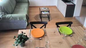 Een woonkamer met een bank, een salontafel en een eettafel met stoelen en borden.