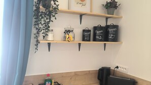 Een keuken met een houten aanrecht, een roestvrijstalen spoelbak en planken met potten en keukengerei.