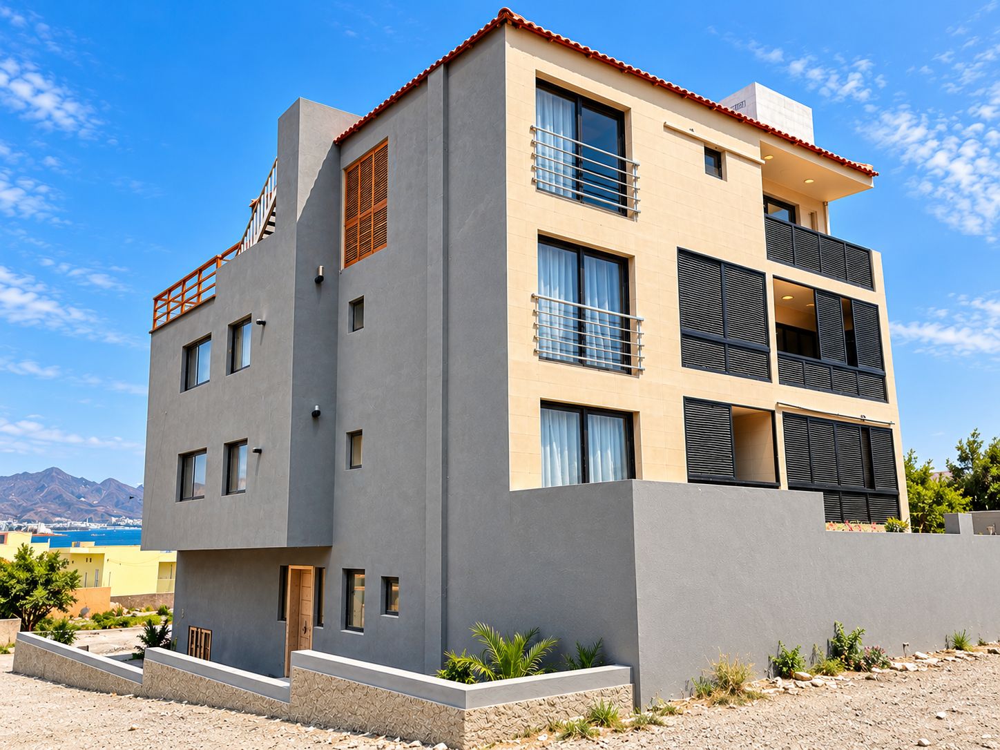 A modern multi-story building with balconies, large windows, and a flat roof.