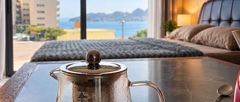Une chambre avec vue sur la mer, un lit et une table avec une théière.