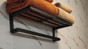 A towel rack with folded towels against a marble wall.
