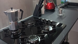 A modern kitchen with a gas stove, kettle, and a sink.