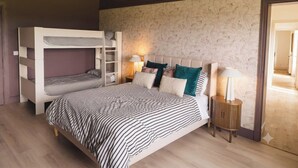 A bedroom with bunk beds, a bedside table with a lamp, and a patterned wallpaper. - Family Ensuite, Balcony & Bunks | Boyne Valley (Drogheda)