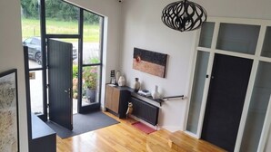 A modern living room with a wooden floor, a black sofa, a dining area with a table, and a large window offering a view of the outdoors. - Family Ensuite, Balcony & Bunks | Boyne Valley (Drogheda)