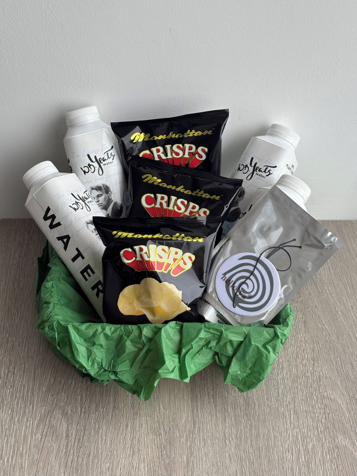 Una cesta de regalo con papas fritas, botellas de agua y un pequeño objeto con diseño en espiral.