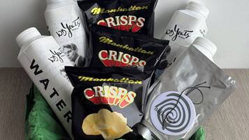 Una cesta de regalo con papas fritas, botellas de agua y un pequeño objeto con diseño en espiral.