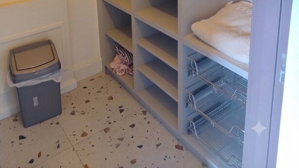 A walk-in closet with multiple shelves, a hanging rod, and a trash bin. - Family Ensuite, Balcony & Bunks | Boyne Valley (Drogheda)
