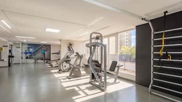 A gym with exercise equipment, a large window, and a view of buildings.
