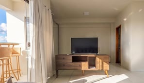 A balcony with a TV, wooden furniture, and a view of the sky. - Studio in Condo w/ Pool in Setor Bueno Bli2903 (Goiânia)