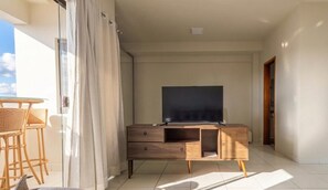 A balcony with a TV, wooden furniture, and a view of the sky.