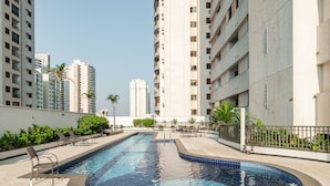 A swimming pool with lounge chairs and a view of high-rise buildings. - Apt in Cond. w/ Pool in Goiania Bli1801 (Goiânia)
