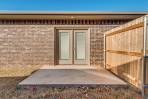 A double garage door with a metal gate, a concrete driveway, and a brick wall. - Delightful 3-bedroom townhome in peaceful Edmond. Right off the I-35 (Edmond)
