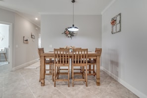 A dining area with a wooden table and chairs, a hanging light fixture, and a wall-mounted picture frame. - Delightful 3-bedroom townhome in peaceful Edmond. Right off the I-35 (Edmond)