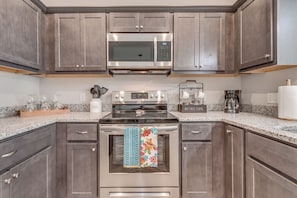 A kitchen with dark wood cabinets, stainless steel appliances, a granite countertop, and a coffee maker. - Delightful 3-bedroom townhome in peaceful Edmond. Right off the I-35 (Edmond)