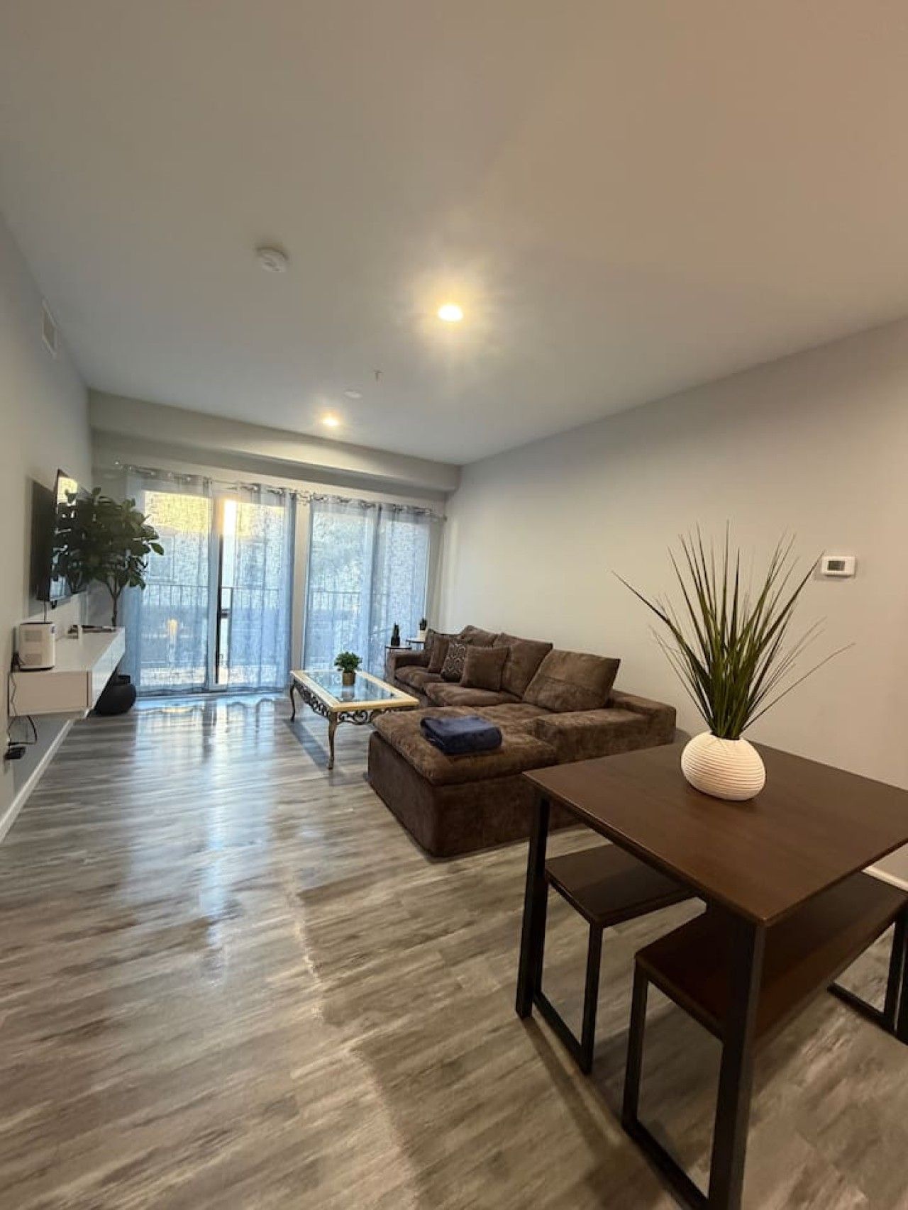 A modern living room with a sofa, coffee table, and a dining table.