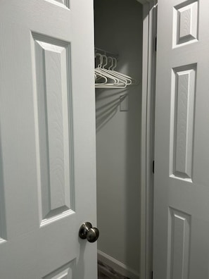 A white door with a modern handle, leading to a hallway with a white wall and a metal rack with clothes. - Perfect Location Old town / walk to the VRE & BARS (Manassas)