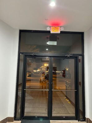 A hotel entrance with a glass door, an exit sign, and a view of the street outside. - Perfect Location Old town / walk to the VRE & BARS (Manassas)