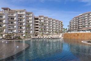 Un resort con edificios de varios pisos, piscina y zonas de estar al aire libre.