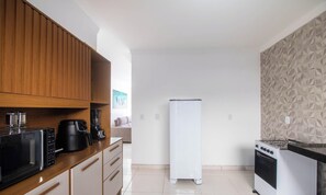 A compact kitchen with wooden cabinets, a coffee maker, a blender, a white refrigerator, and a gas stove. - House w/ 2 Suites in a Cond. w/ Pool Blv0002 (Porto Seguro)