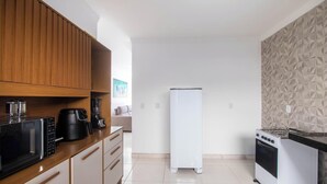 Eine kleine Küche mit Holzausstattung, einer schwarzen Kaffeemaschine, einem weißen Kühlschrank und einem Gaskochfeld.