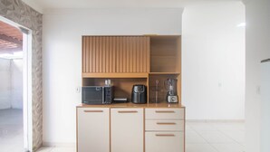 Eine kleine Küche mit einer Mikrowelle, einer Kaffeemaschine und einem Mixer auf einem Holzschrank.