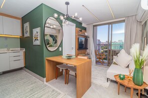 Eine moderne Wohnung mit Küche, Essbereich und Wohnzimmer. Es gibt einen großen Spiegel, einen Esstisch mit Stühlen, eine Couch und einen kleinen Beistelltisch mit Dekoration.