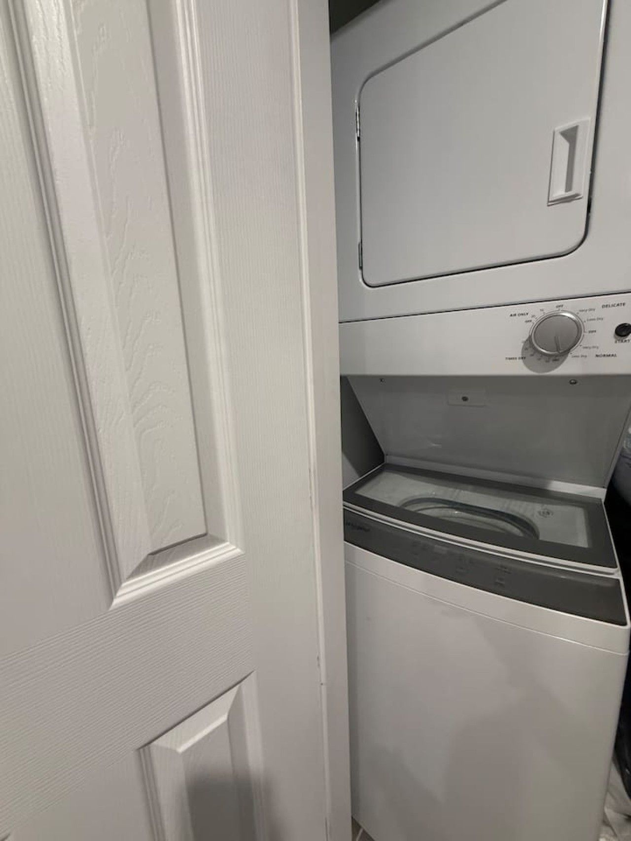 Une porte blanche avec un panneau texturé et un lave-linge blanc doté d’un panneau de commande.
