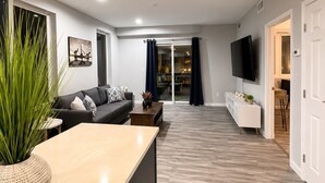 A modern living room with a sofa, coffee table, and a TV mounted on the wall. - Old Town Manassas Sleeps 4 next to bars and restaurants ,  WALK TO VRE (Manassas)