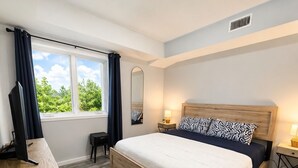 A modern bedroom with a wooden bed, a desk, and a window with curtains. - Old Town Manassas Sleeps 4 next to bars and restaurants ,  WALK TO VRE (Manassas)