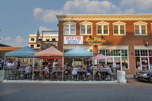 A brick building with a storefront labeled 'C.J. FINZ' and outdoor seating with tents.