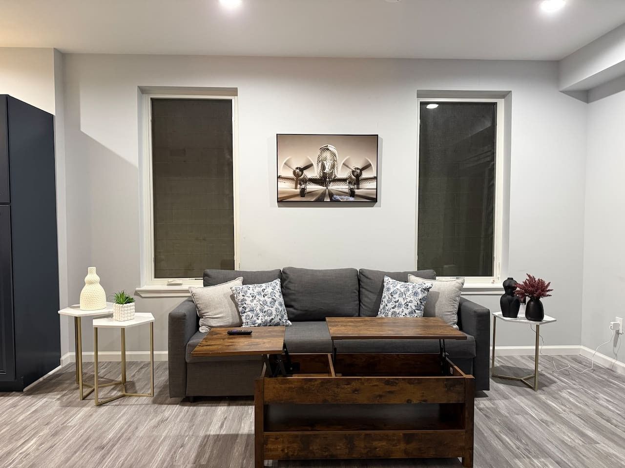 A modern living room with a grey sofa, a wooden coffee table, and a painting above the sofa.