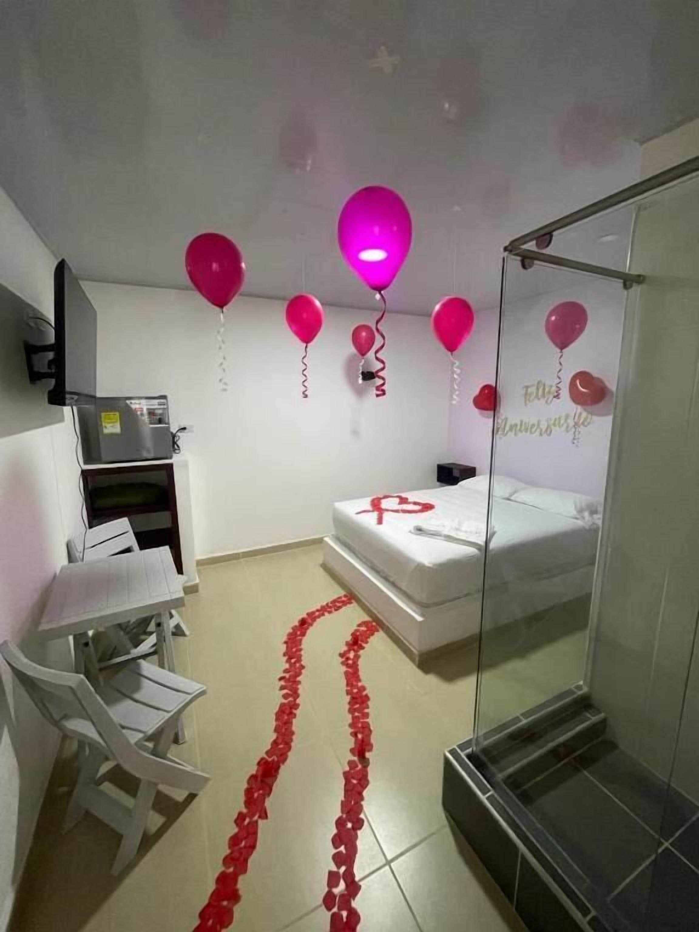A hotel room with a bed, a desk, a chair, and a shower area.