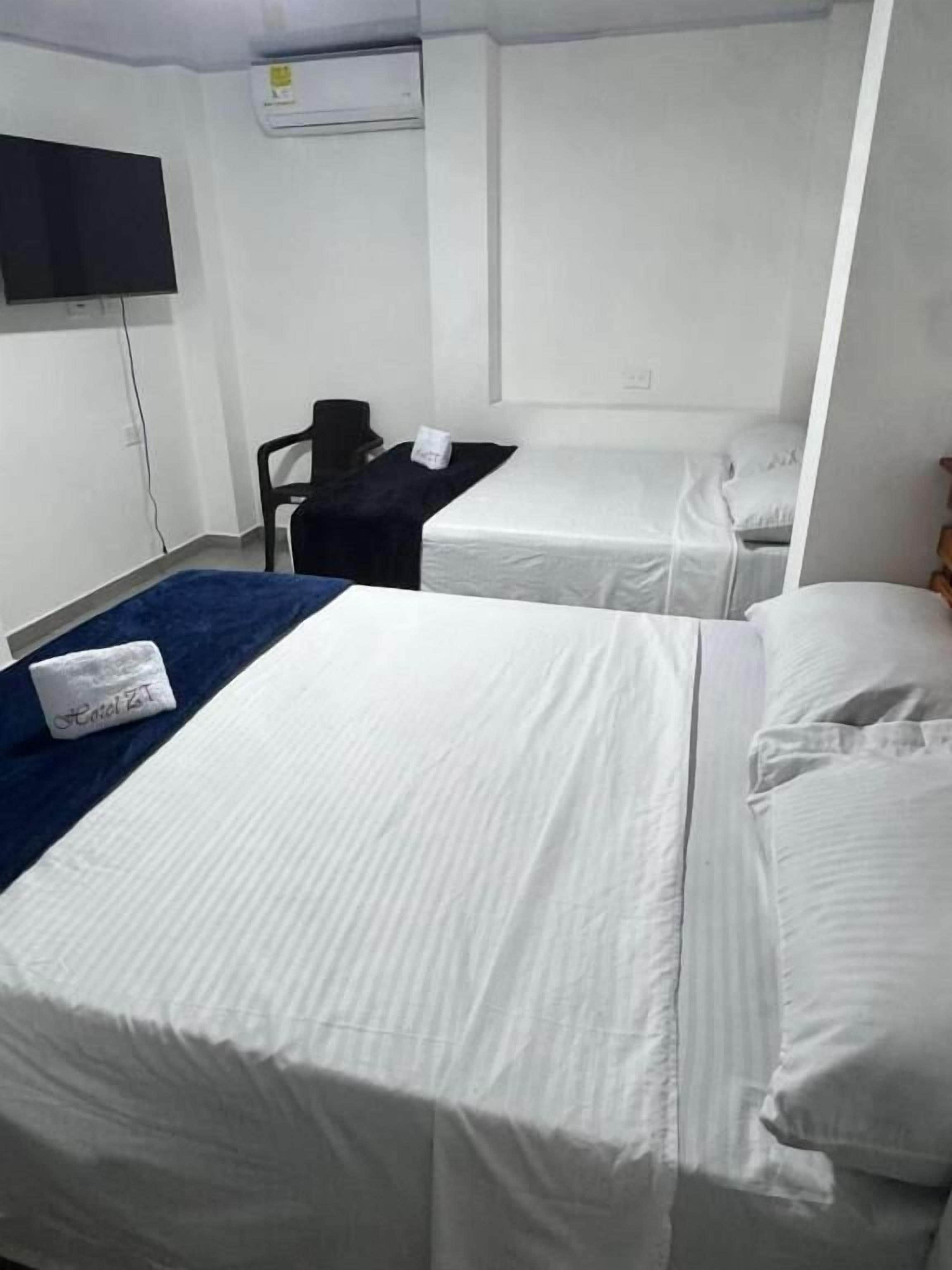 A hotel room with two beds, a flat-screen TV, a desk, and a chair.