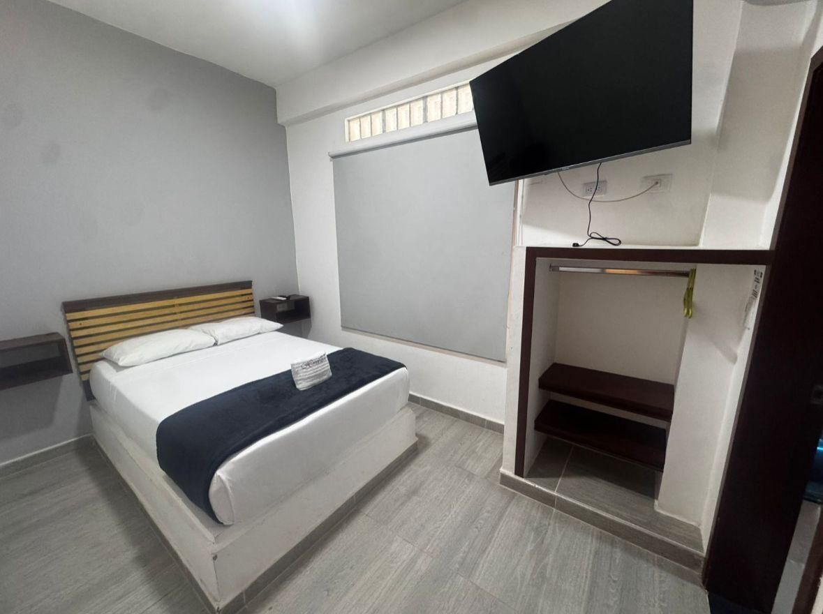 Une chambre d’hôtel comprenant un lit, un téléviseur à écran plat fixé au mur et un placard intégré avec une porte coulissante.