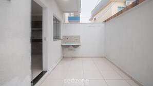 A narrow, enclosed outdoor space with a tiled floor, a small shelf, and a glass door leading to an interior room. - House w/ 2 Suites in a Cond. w/ Pool Blv0004 (Porto Seguro)
