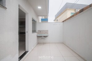 A narrow, enclosed outdoor space with a tiled floor, a small shelf, and a glass door leading to an interior room. - House w/ 2 Suites in a Cond. w/ Pool Blv0004 (Porto Seguro)