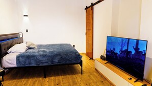 Ein Schlafzimmer mit einem Bett, einem Fernseher und Holzboden.