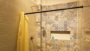 Ein Badezimmer mit Duschvorhang, Handtuchhalter und einer Wand mit gemusterten Fliesen.